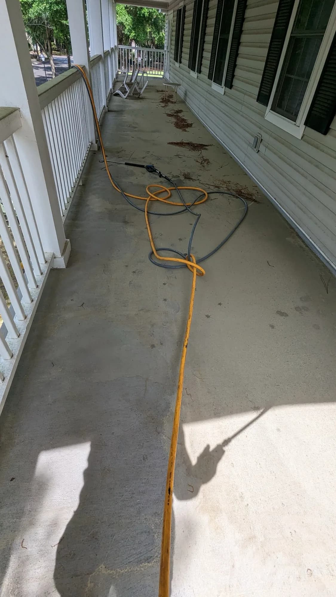 Covered porch floor with hose laid out before washing